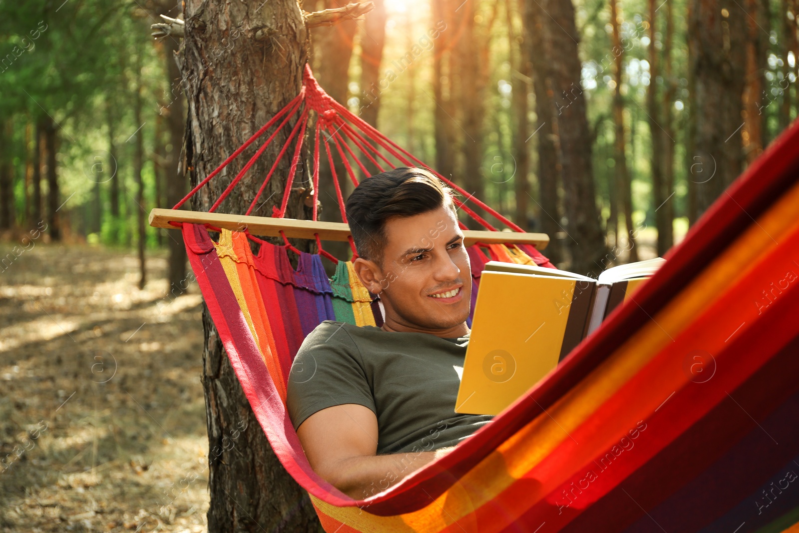 Photo of Man with book relaxing in hammock outdoors on summer day