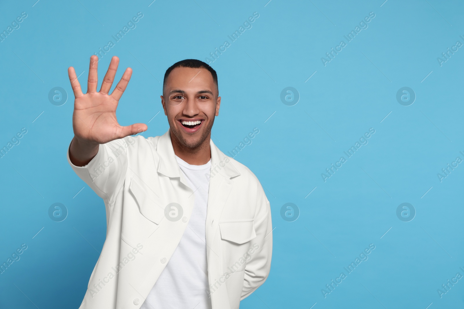 Photo of Man giving high five on light blue background. Space for text