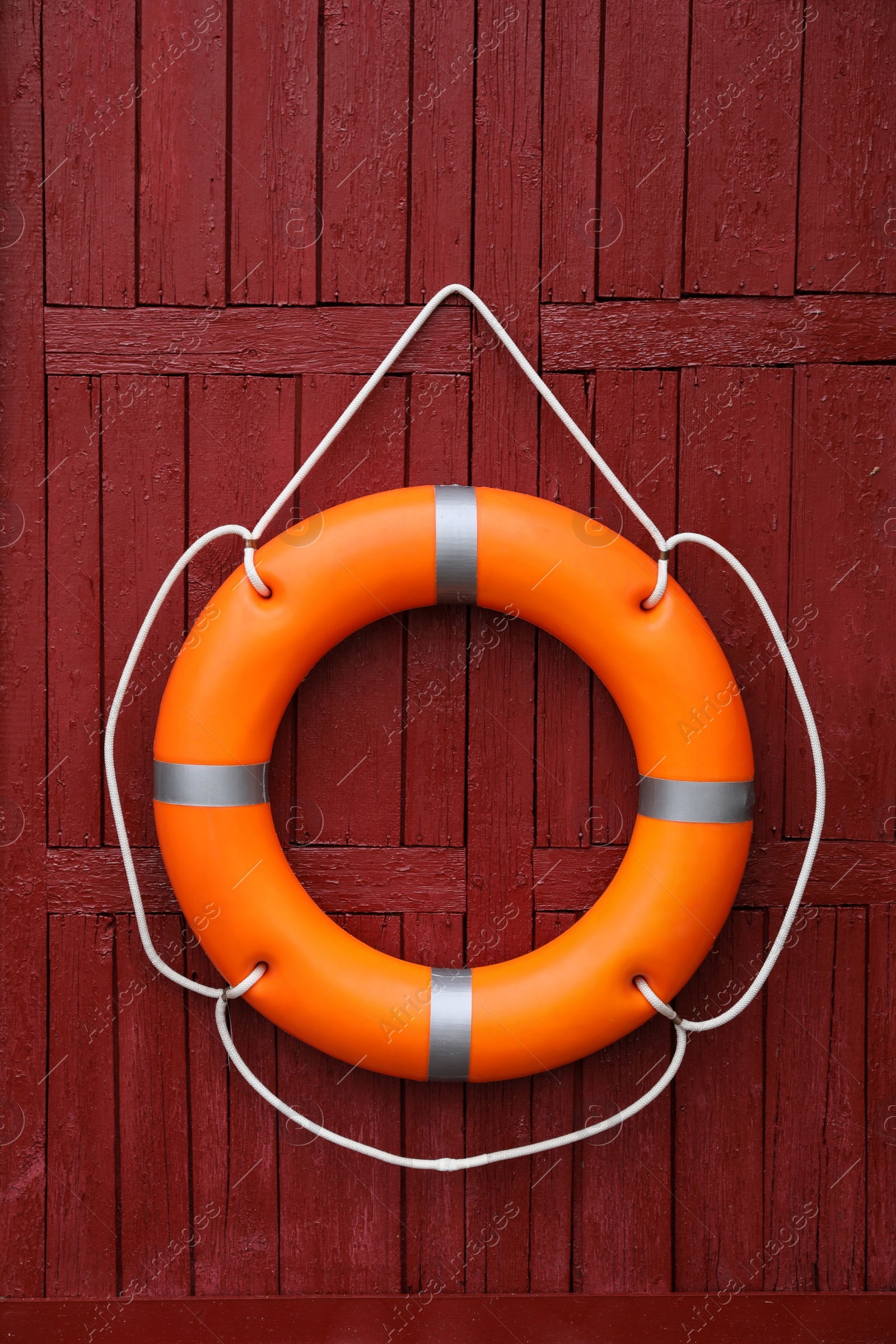 Photo of Orange life buoy hanging on red wooden wall