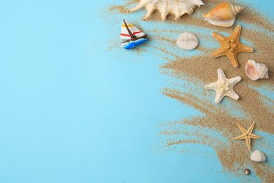Flat lay composition with beautiful sea stars and sand on light blue background. Space for text