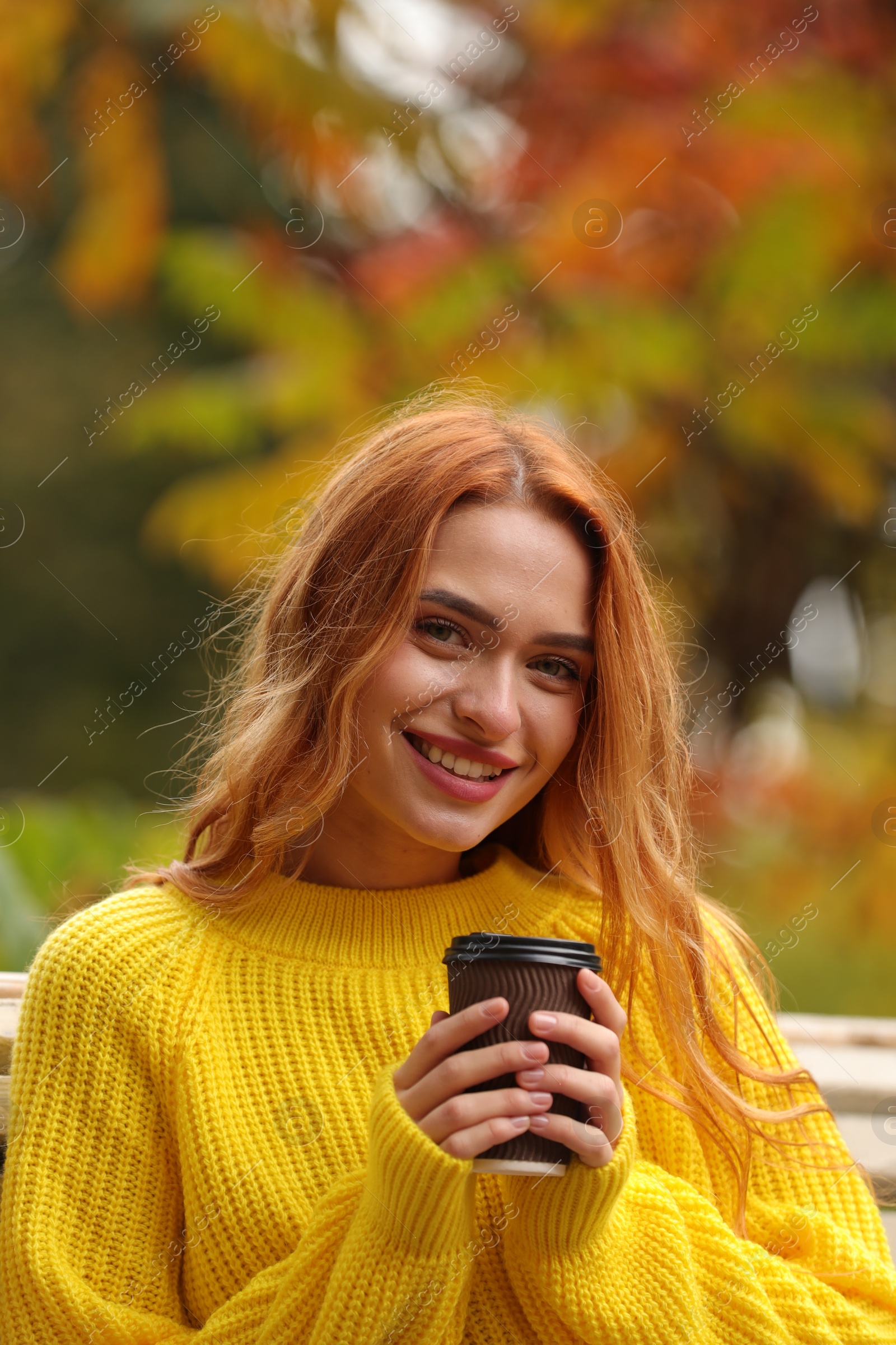 Photo of Portrait of smiling woman with paper cup enjoying autumn outdoors