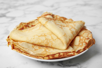 Stack of fresh thin pancakes on white marble table