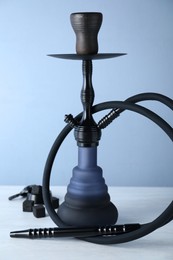 Traditional hookah on white table against light blue background