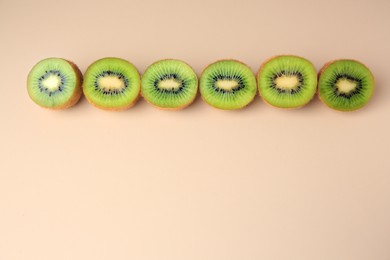 Photo of Halves of fresh kiwis on beige background, flat lay