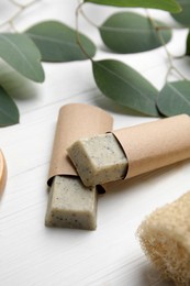 Photo of Soap bars and green leaves on white wooden table. Eco friendly personal care product