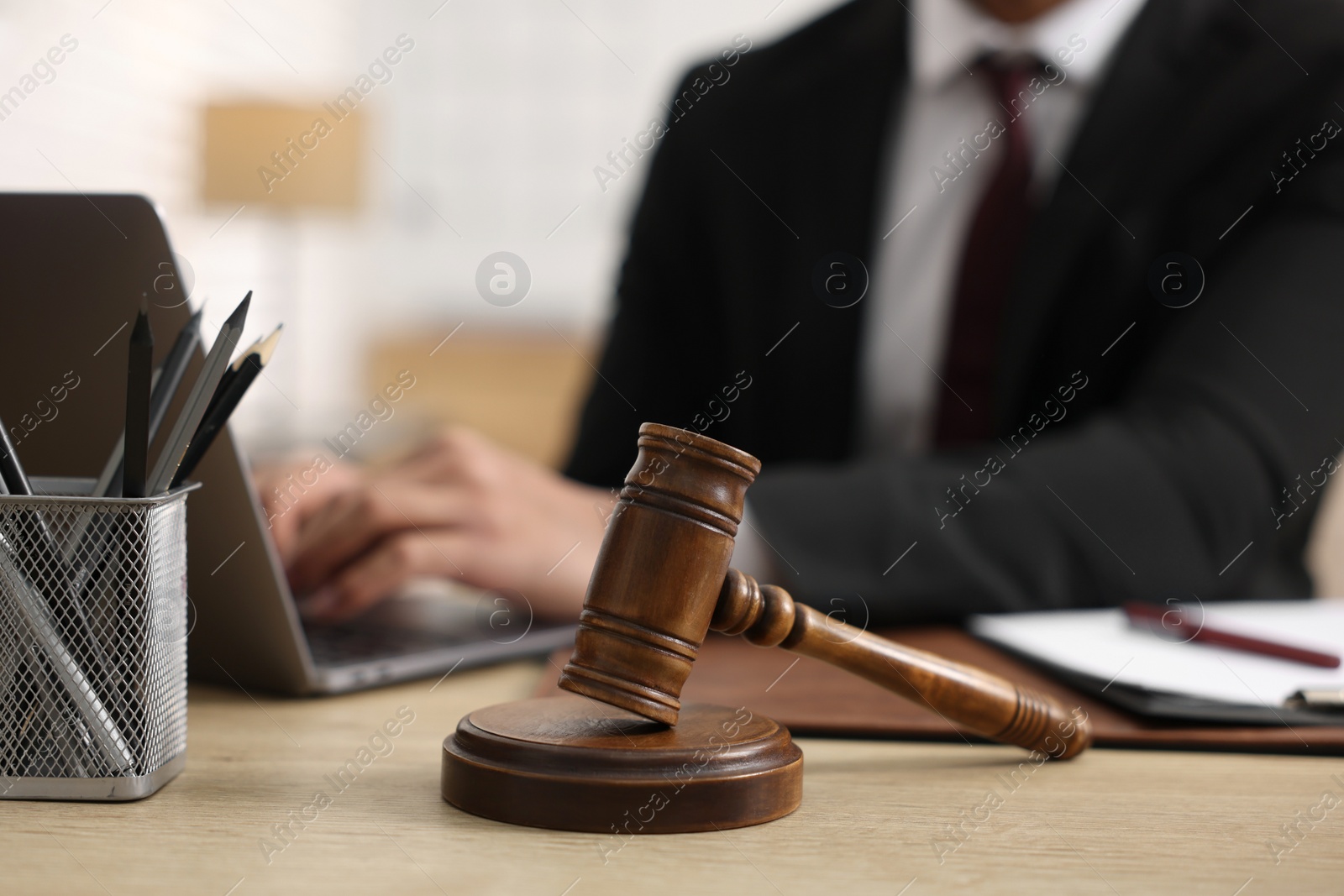 Photo of Lawyer working with laptop at table in office, focus on gavel