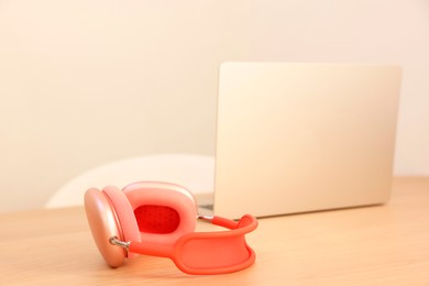 Photo of Modern headphones and laptop on wooden table. Space for text