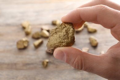 Photo of Man holding gold nugget on blurred background, closeup