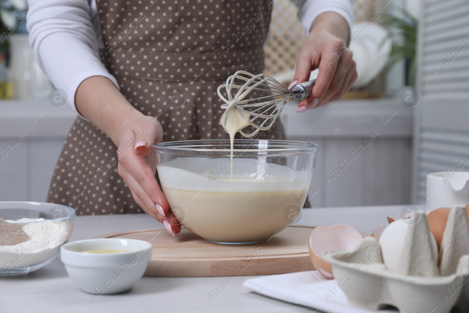 Photo of Woman making dough with whisk in bowl at table, closeup