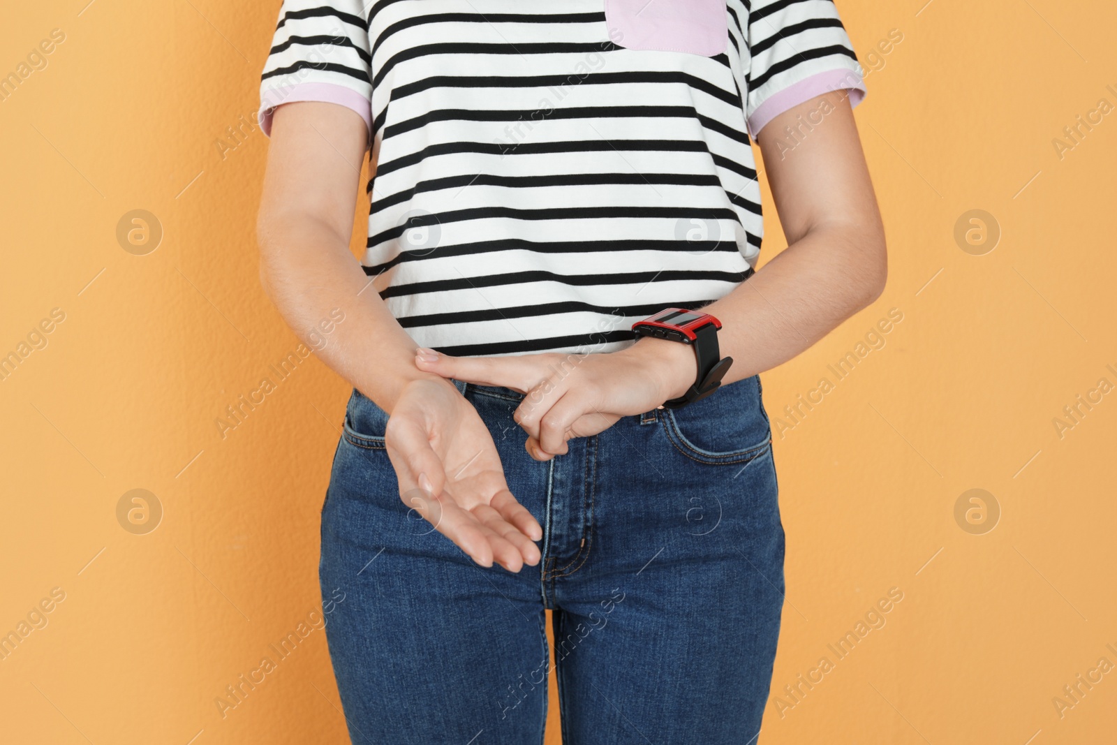 Photo of Woman checking pulse against color background, closeup