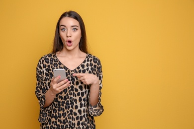 Attractive young woman using mobile phone on color background