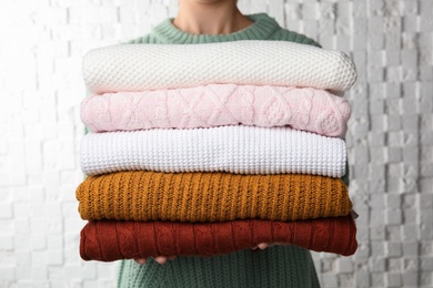 Photo of Woman holding stack of warm clothes on white background, closeup. Autumn season