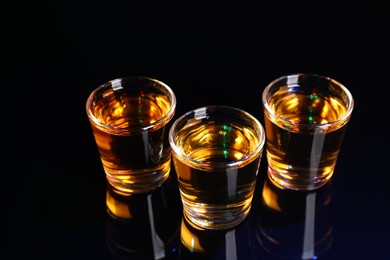Alcohol drink in shot glasses on mirror surface