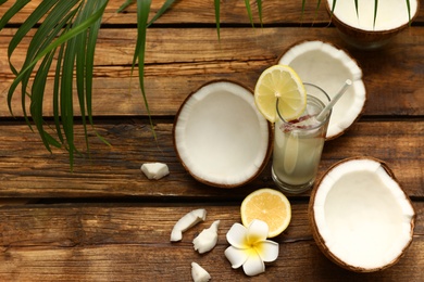 Photo of Composition with glass of coconut water and lemon on wooden table. Space for text