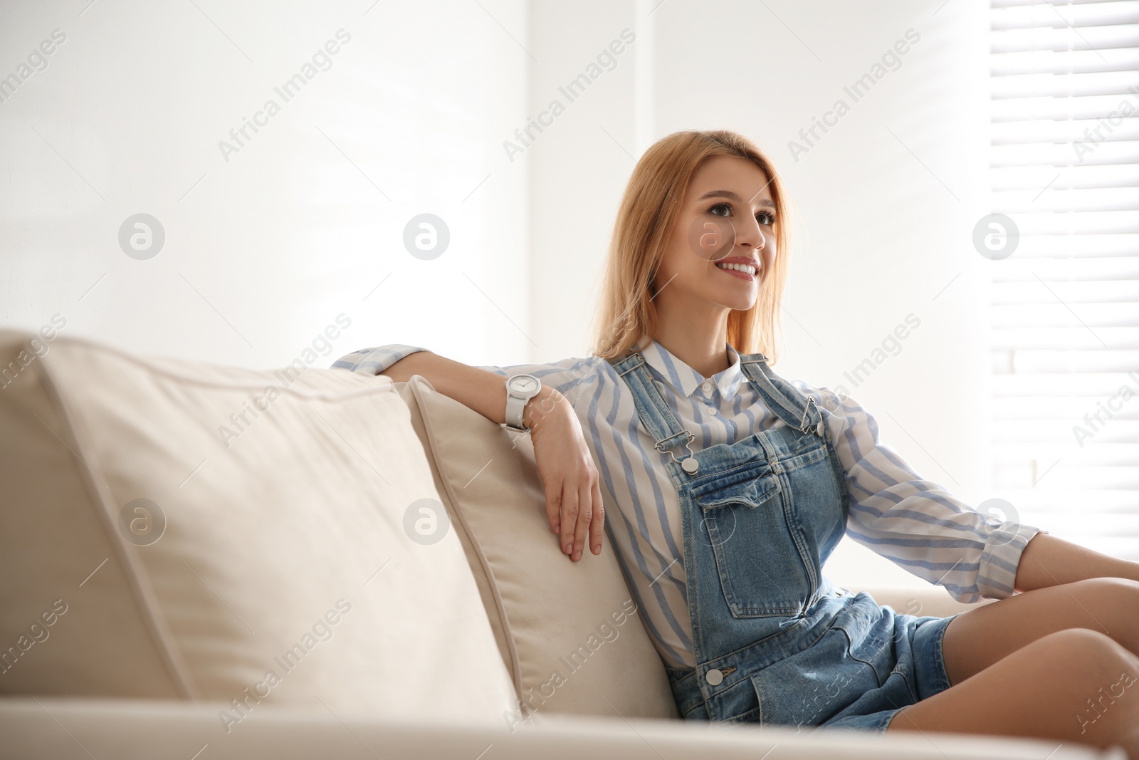 Photo of Young woman relaxing on couch near window at home