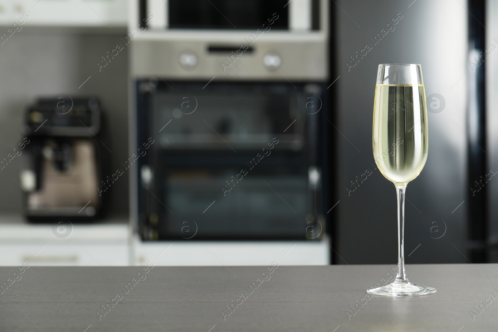 Photo of Glass of wine on grey table in kitchen. Space for text