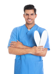 Male orthopedist showing insoles on white background