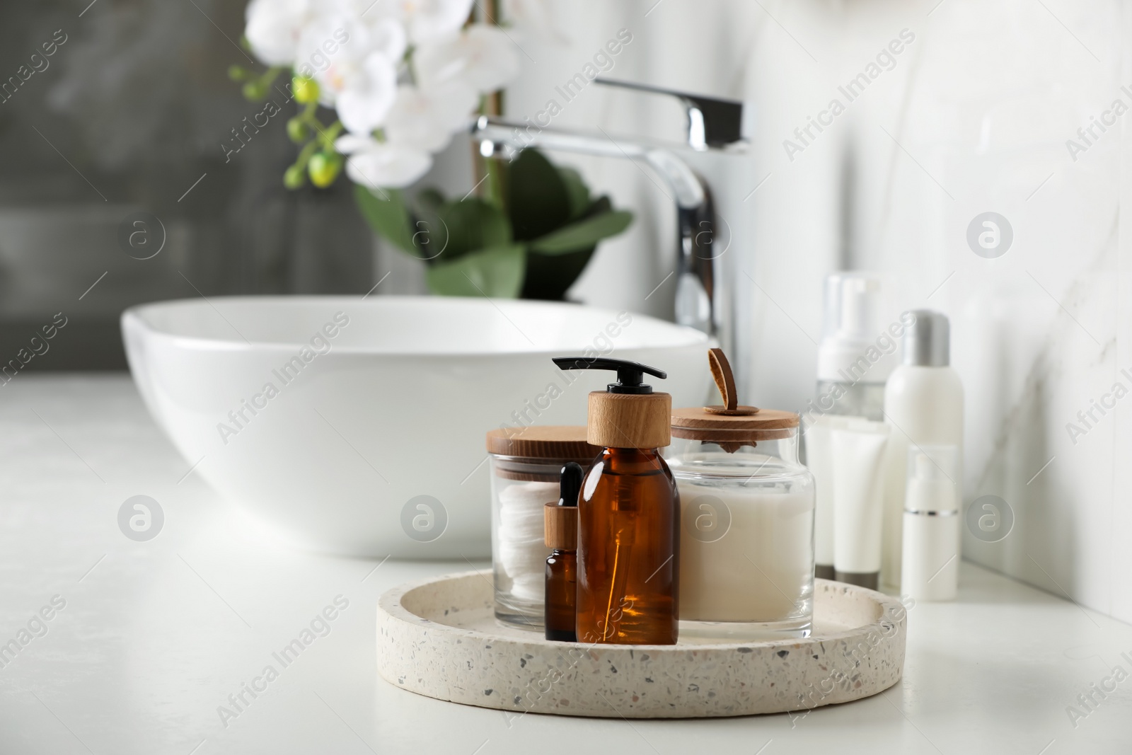 Photo of Tray with dispenser bottle and cosmetic products on white table in bathroom