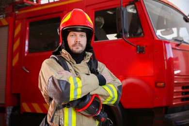 Photo of Firefighter in uniform near red fire truck at station