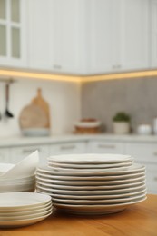 Clean plates and bowls on wooden table in kitchen