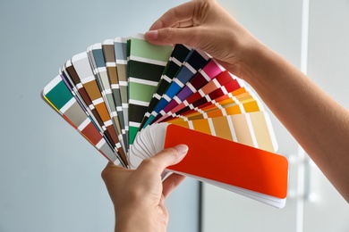 Photo of Female interior designer with color palette samples indoors, closeup