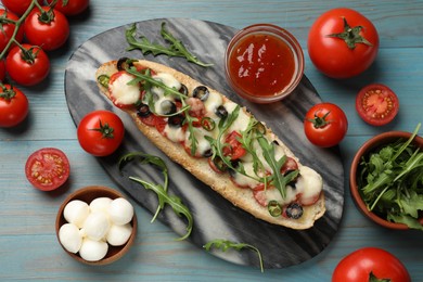 Photo of Tasty pizza toast and ingredients on light blue wooden table, top view