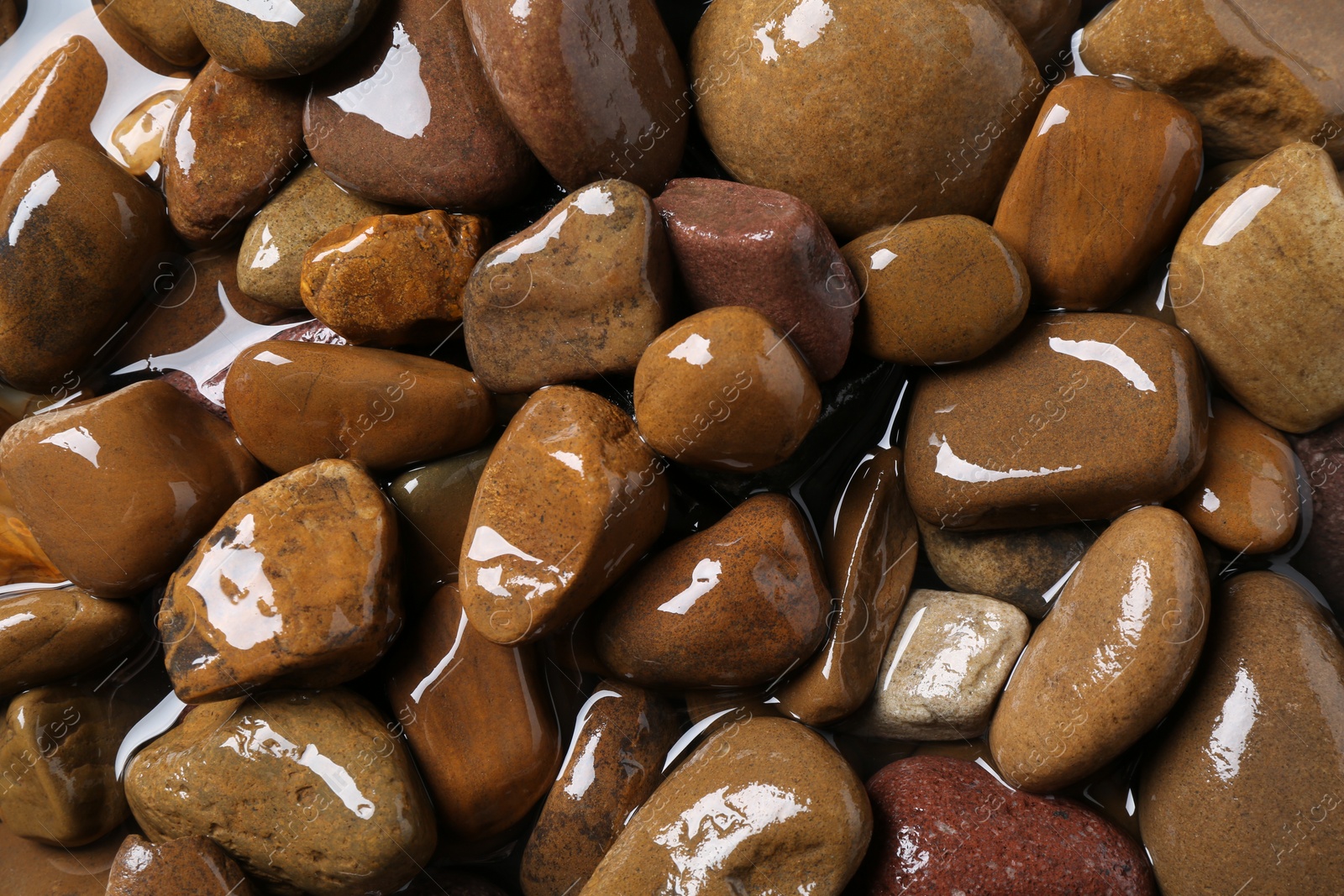 Photo of Beautiful pebbles in water as background, top view