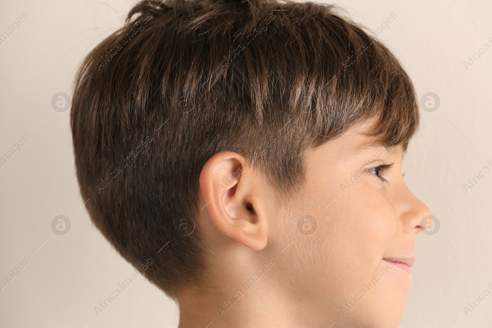 Photo of Cute little boy on light background, closeup. Hearing problem