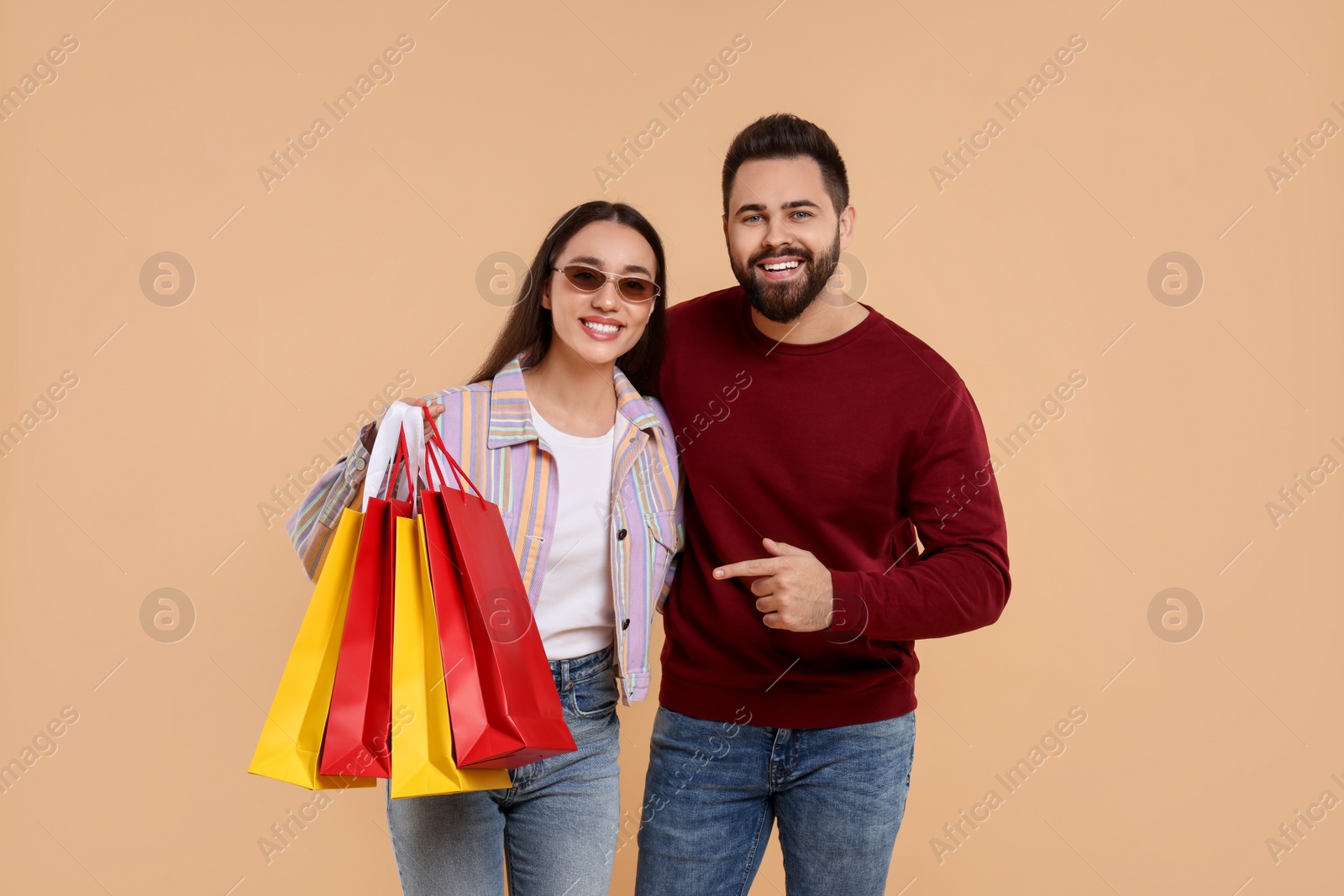 Photo of Happy couple with shopping bags on beige background