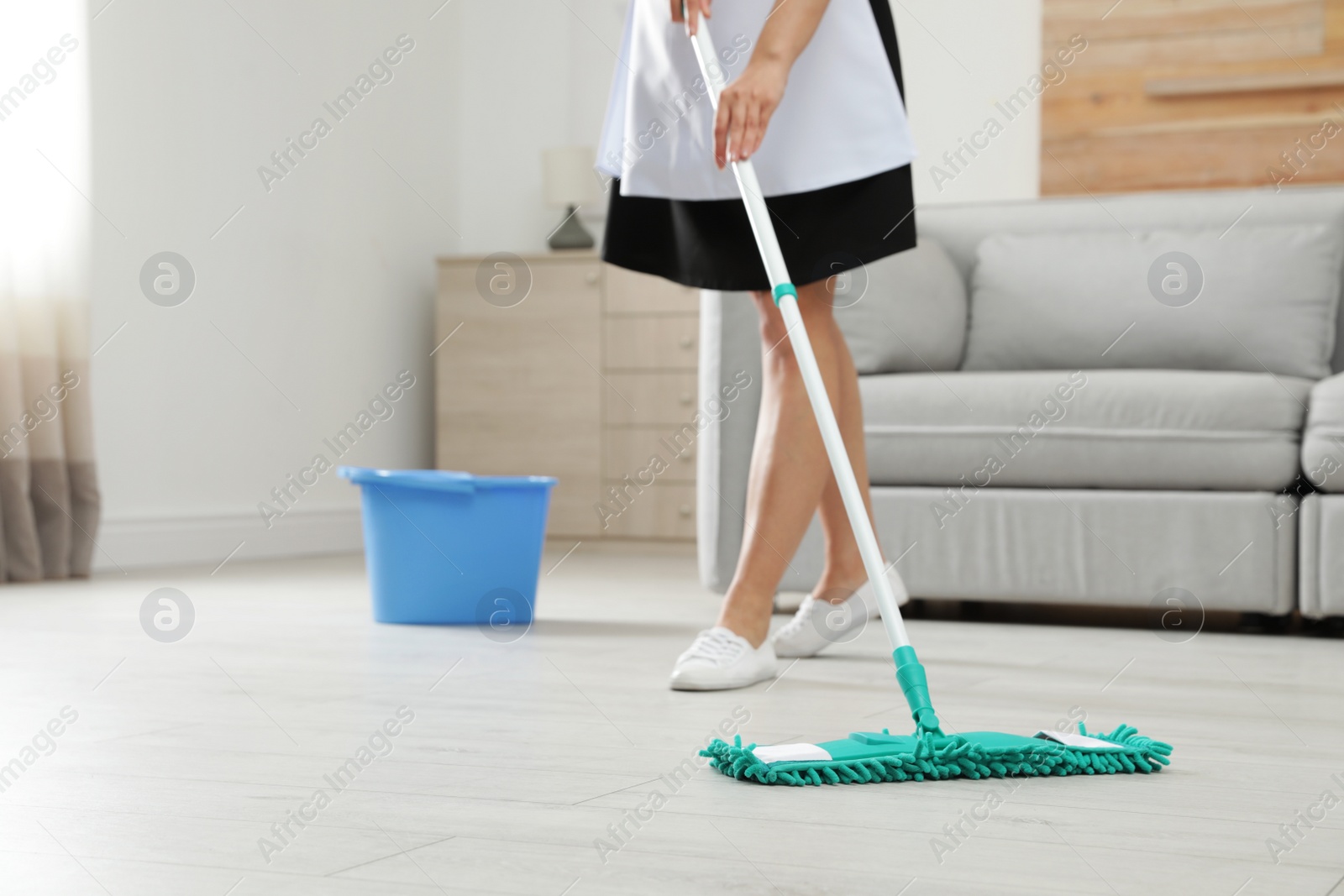 Photo of Young maid washing floor with mop in hotel room, closeup