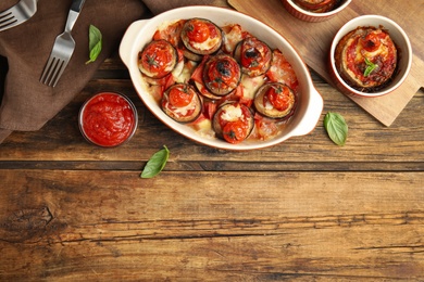 Baked eggplant with tomatoes, cheese and basil served on wooden table, flat lay. Space for text