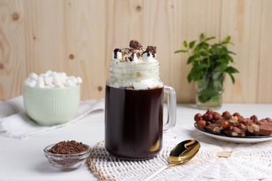 Photo of Mason jar of delicious hot chocolate with whipped cream on white table