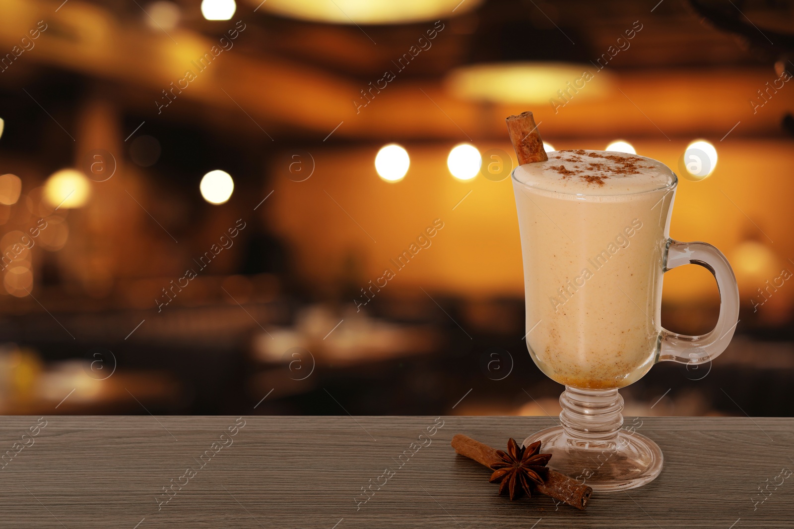 Image of Glass of delicious eggnog on table in bar, space for text