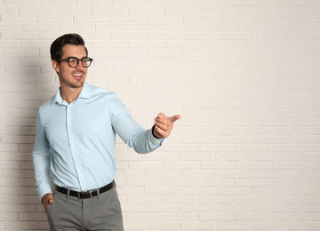 Young male teacher with glasses near brick wall. Space for text