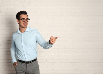 Photo of Young male teacher with glasses near brick wall. Space for text