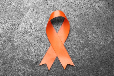Photo of Orange ribbon on grey table, top view. Multiple sclerosis awareness