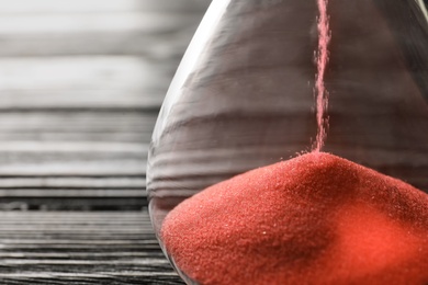 Photo of Hourglass with flowing sand on table, closeup. Time management