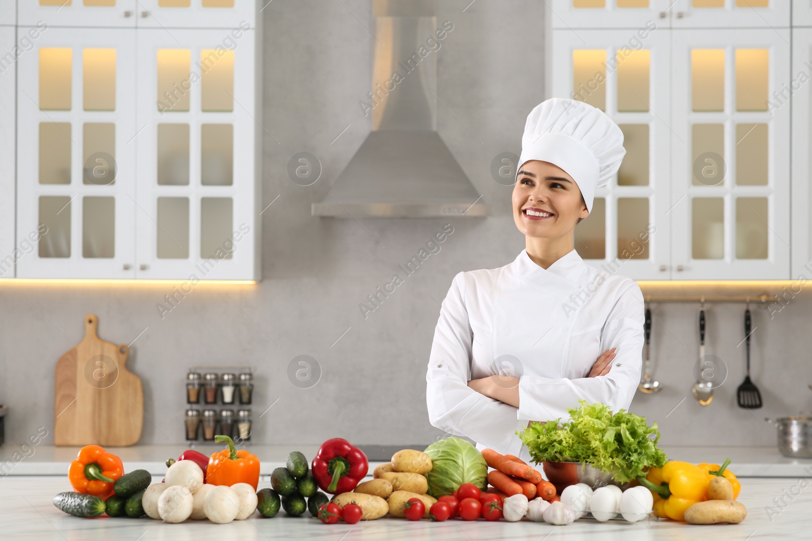 Photo of Happy chef near fresh vegetables at table in kitchen. Space for text