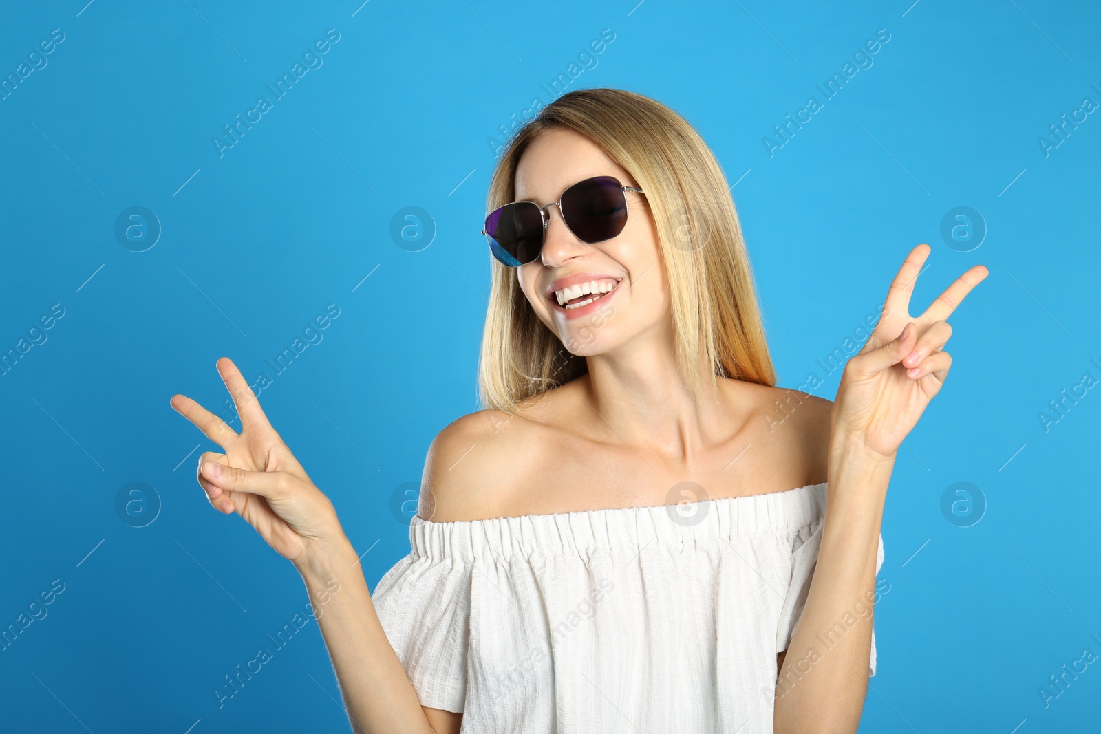 Photo of Beautiful woman in stylish sunglasses on light blue background