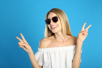 Photo of Beautiful woman in stylish sunglasses on light blue background