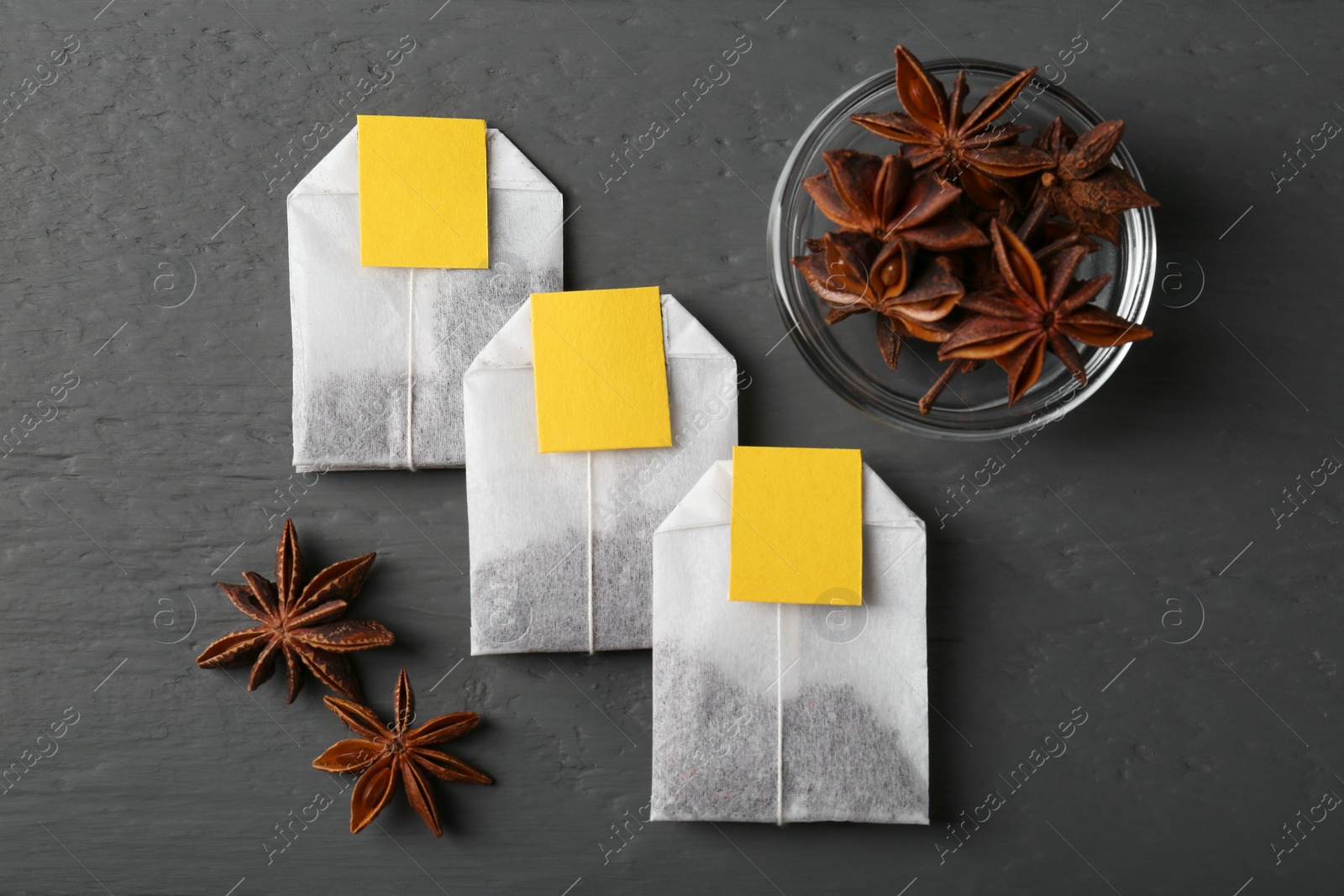 Photo of Tea bags and anise stars on grey wooden table, flat lay