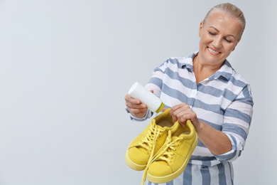 Woman putting powder shoe freshener in footwear on white background. Space for text