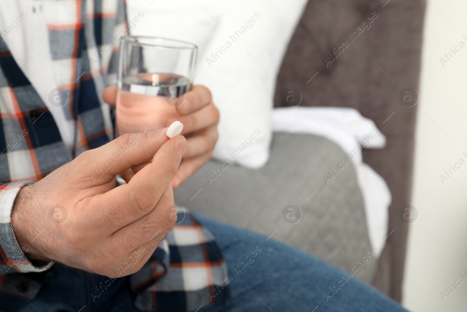 Photo of Man with pill and glass of water indoors, closeup