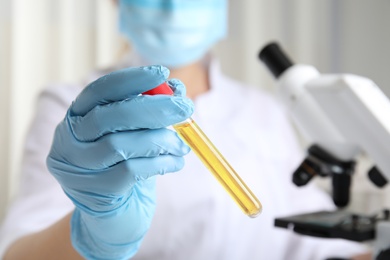 Photo of Doctor holding test tube with urine sample for analysis in laboratory, closeup