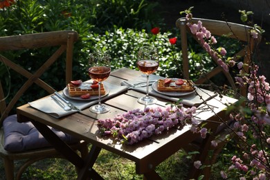 Delicious Belgian waffles with fresh strawberries and wine served on table in spring garden