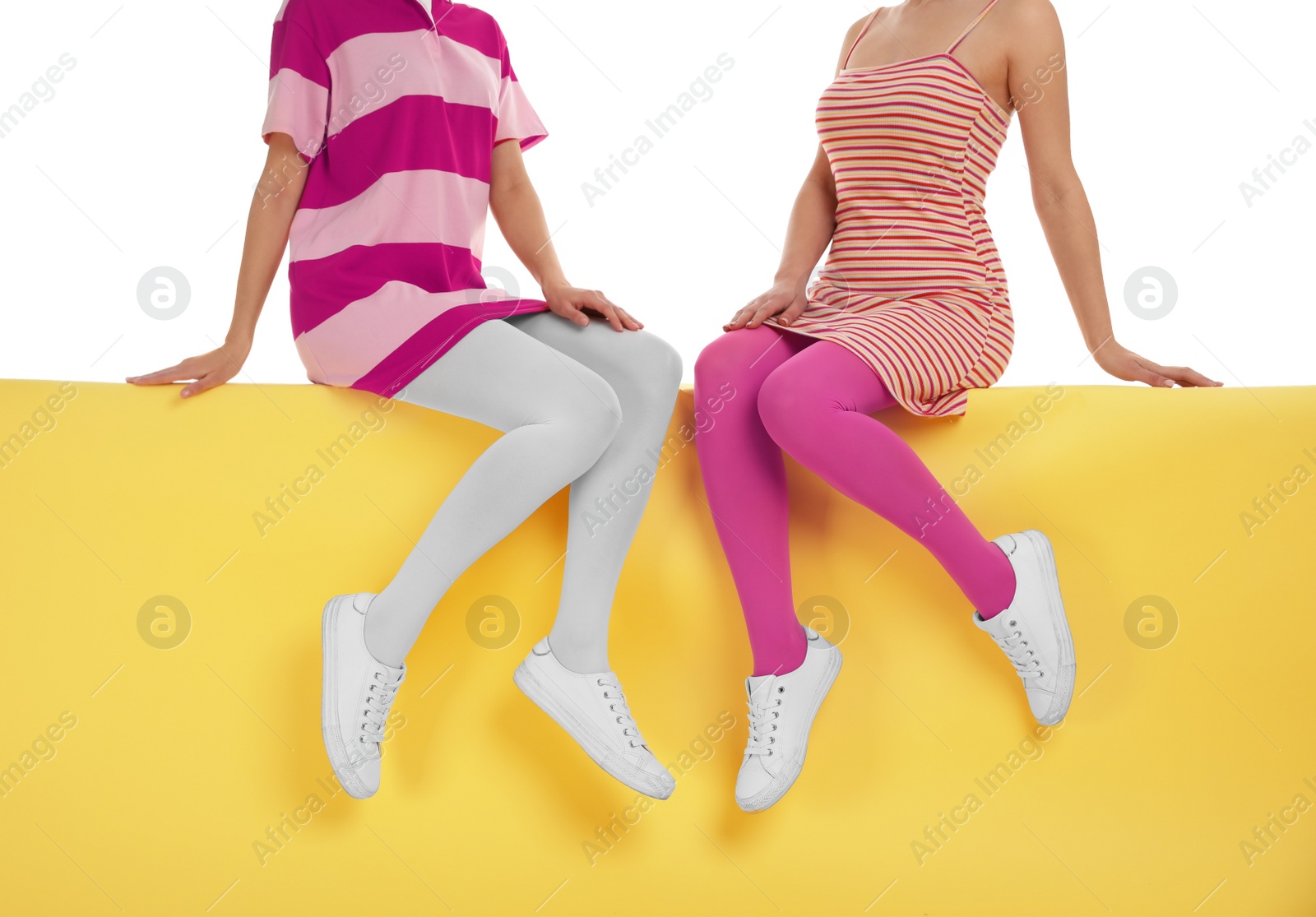 Photo of Women wearing bright tights sitting on color background, closeup