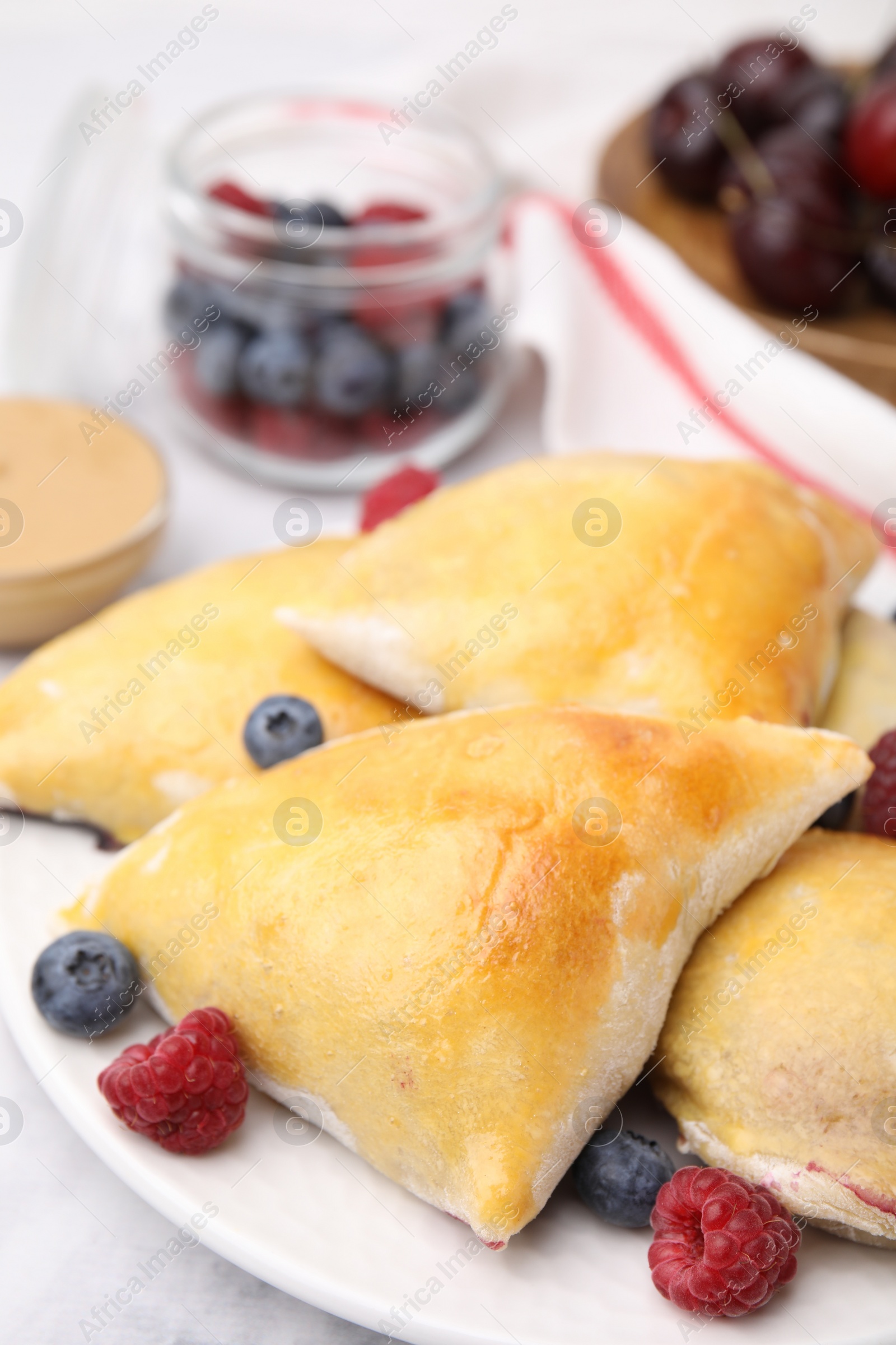 Photo of Delicious samosas with berries on white marble table, closeup