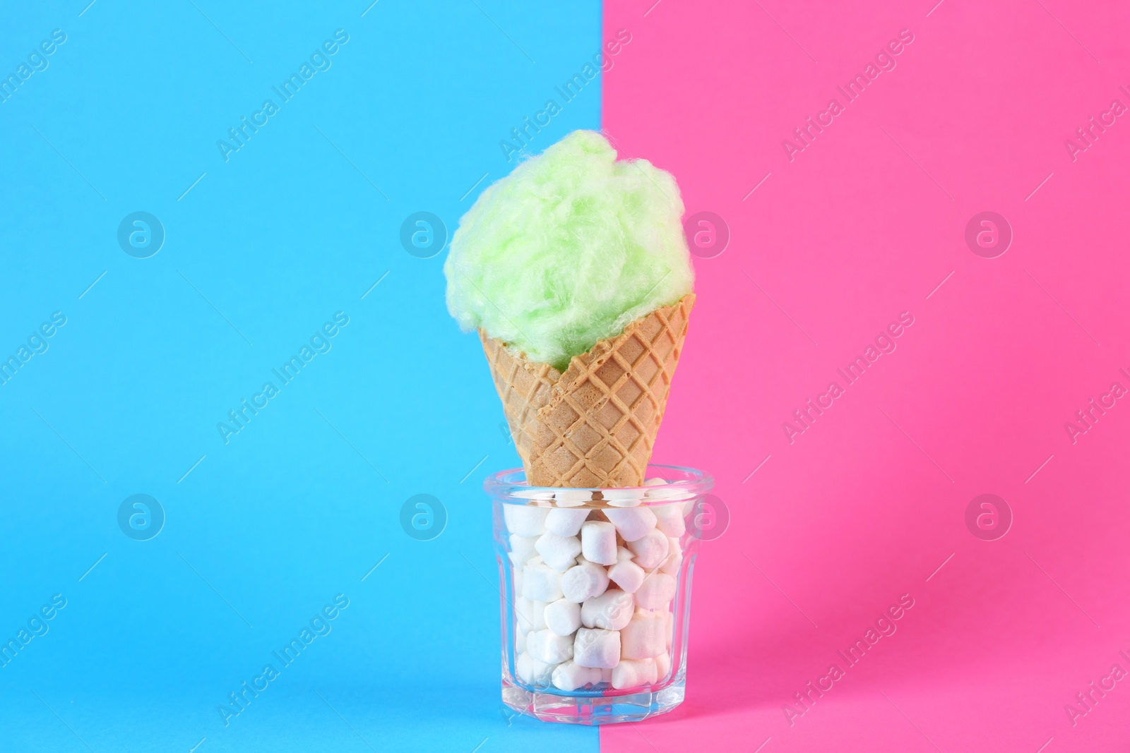 Photo of Sweet cotton candy in waffle cone on color background