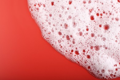 Photo of White foam with bubbles on red background, top view. Space for text