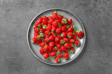 Photo of Plate with ripe strawberries on grey background, top view